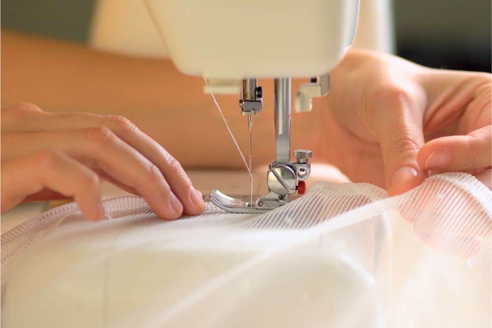The rolled edge of the fabric is placed under the presser foot of the sewing machine.