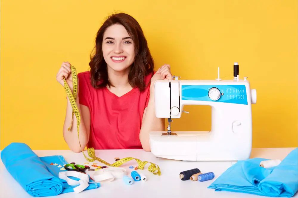 Close up portrait of charming woman seamstress sitting at table with sewing machine