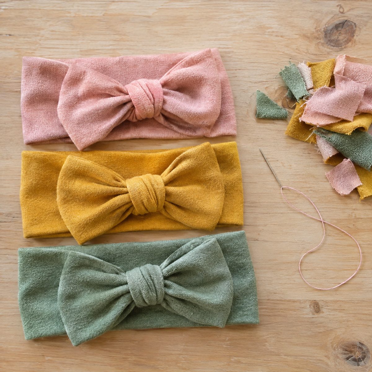 Three soft fabric headband bows in pink, mustard and sage