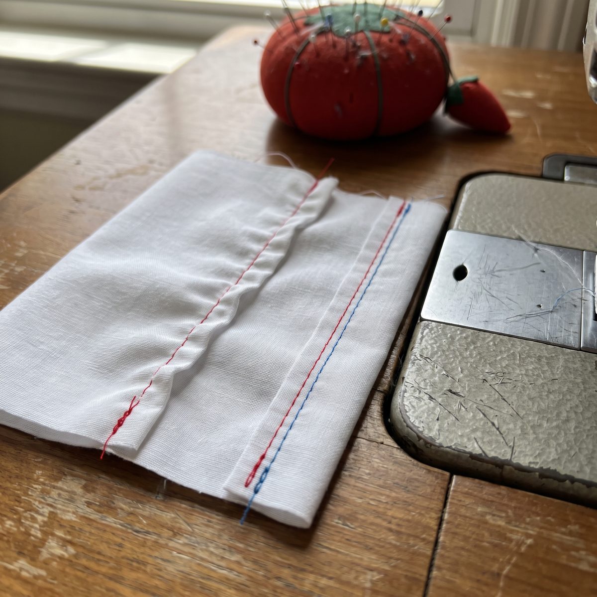 Test seams on white scrap fabric showing tight versus balanced tension