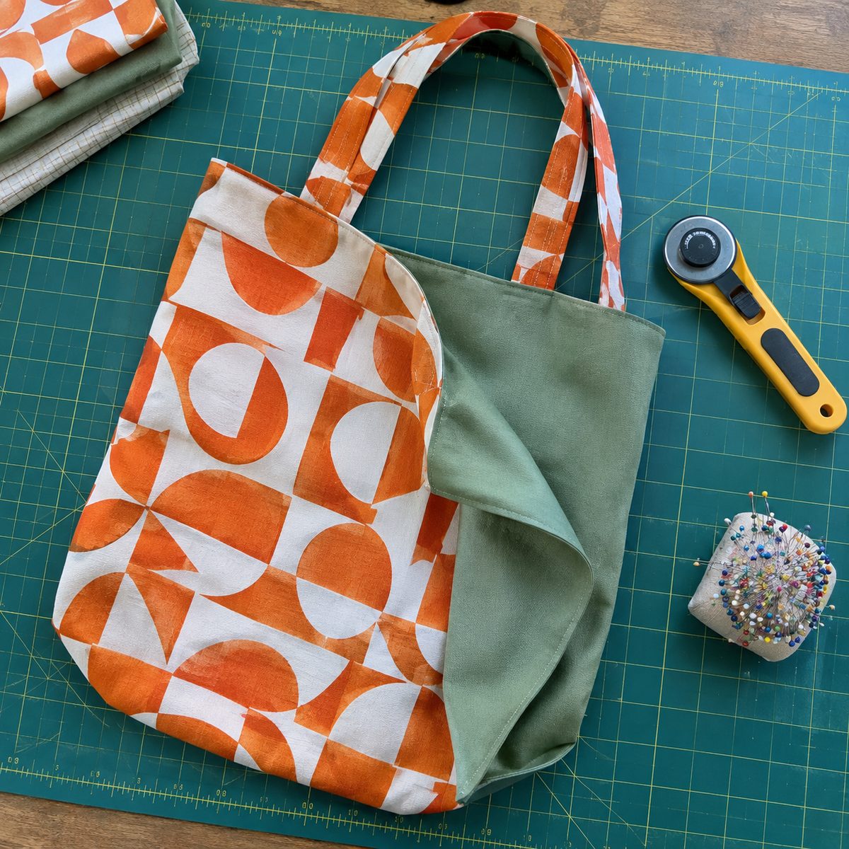 Reversible tote folded to show orange geometric print and sage green sides