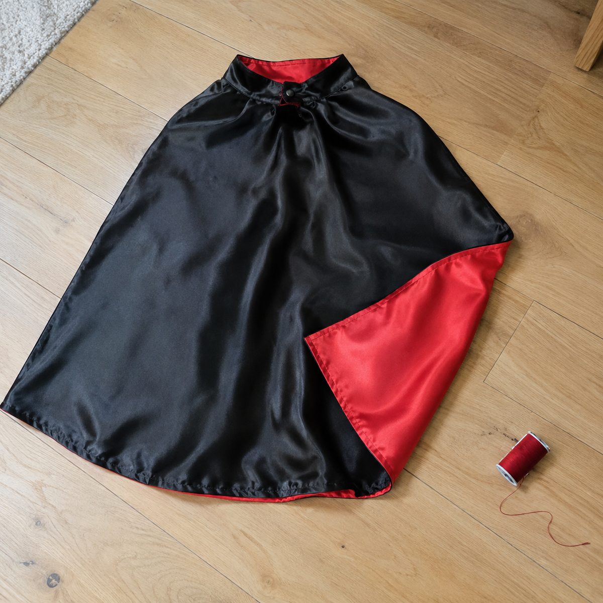 Reversible black and red kids superhero cape laid flat