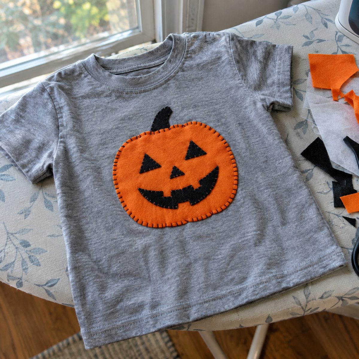 Gray T-shirt with jack-o'-lantern appliqué on an ironing board