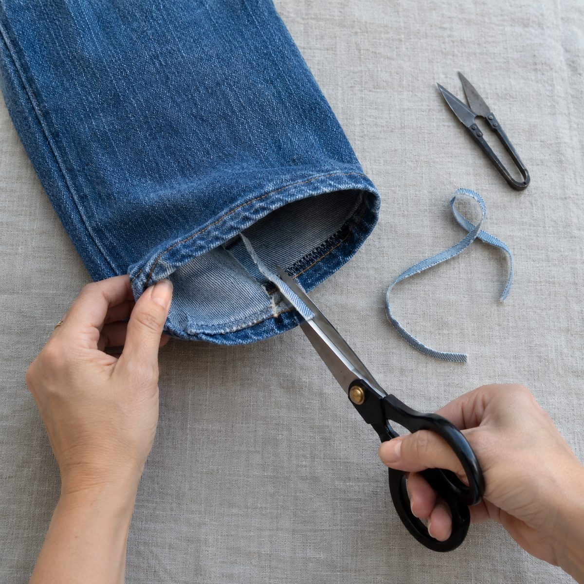 Trimming the excess denim from inside the tuck, leaving a short seam allowance