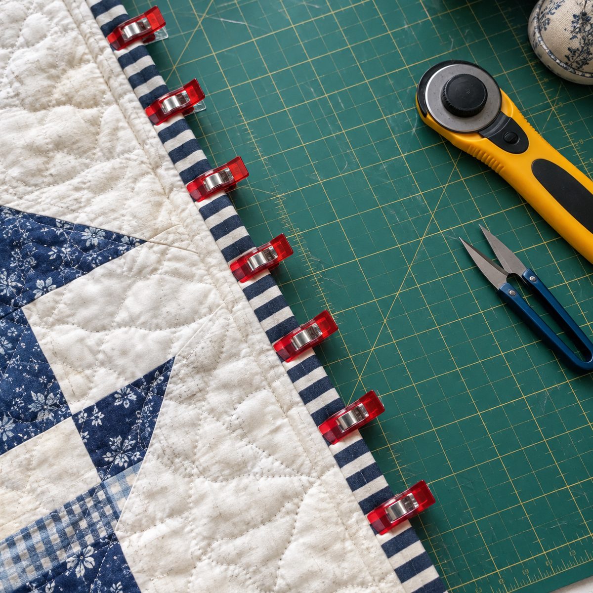 Quilt binding held with a row of red sewing clips instead of pins