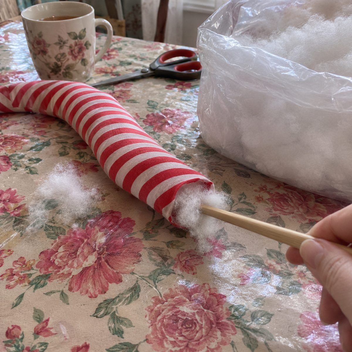 Chopstick pushing fiberfill into a striped cotton tube for a mini fabric wreath