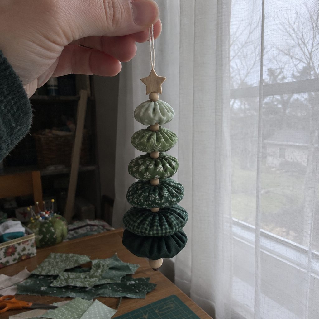 Hanging yo-yo tree ornament made from five green fabric yo-yos threaded with small wooden beads, held up by its loop