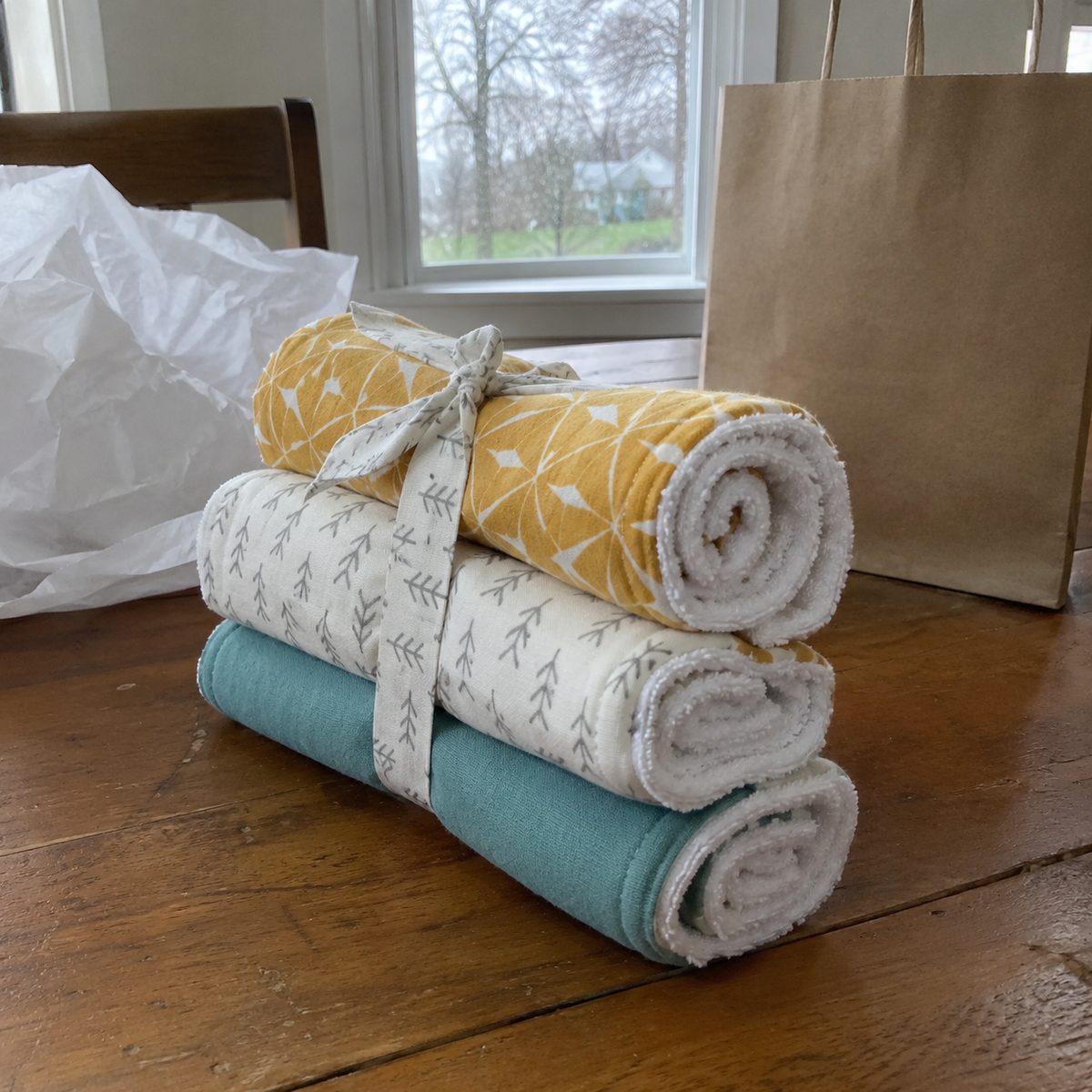 Set of three rolled handmade burp cloths in coordinating prints tied with a fabric strip as a gift