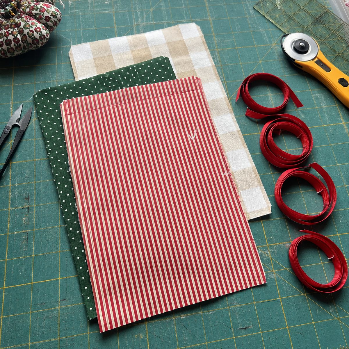 Cut cotton rectangles and ribbon lengths for three sizes of fabric gift bag laid on a cutting mat