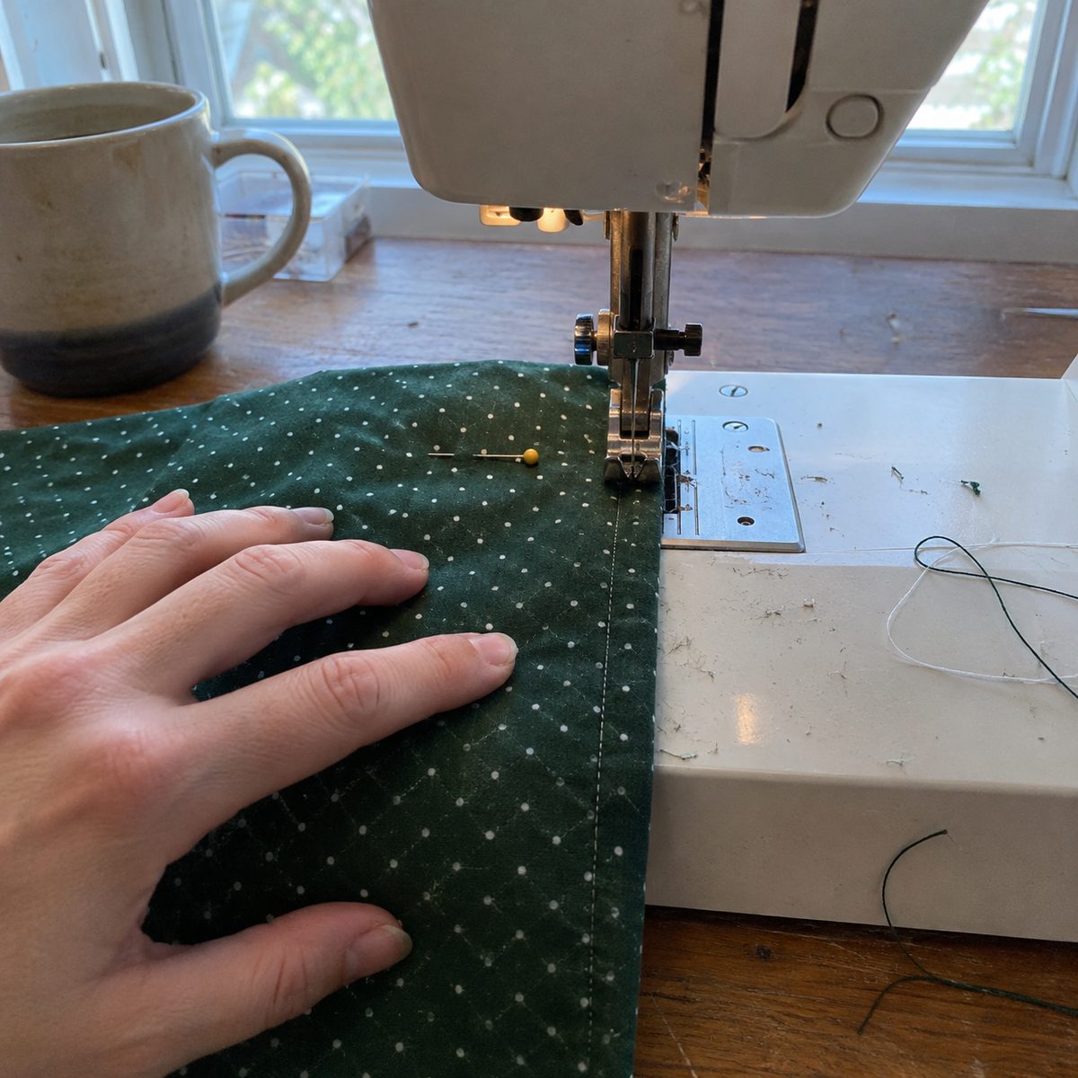 Sewing the first pass of a French seam on a fabric gift bag, stopping at a pin two inches from the top