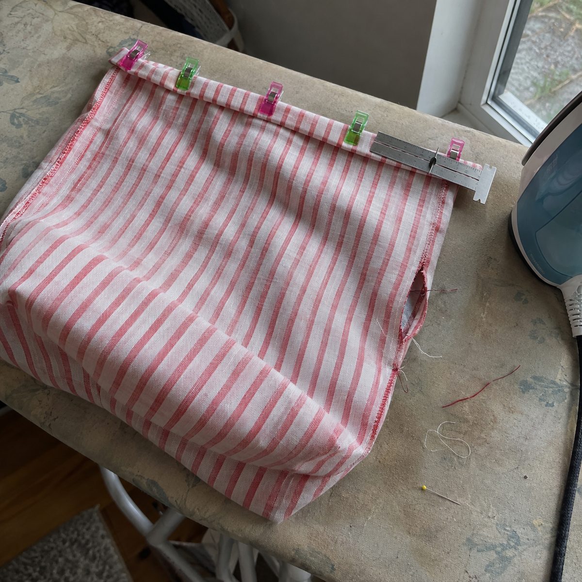 Casing on a fabric gift bag folded and clipped before stitching, with the drawstring slot at the side seam
