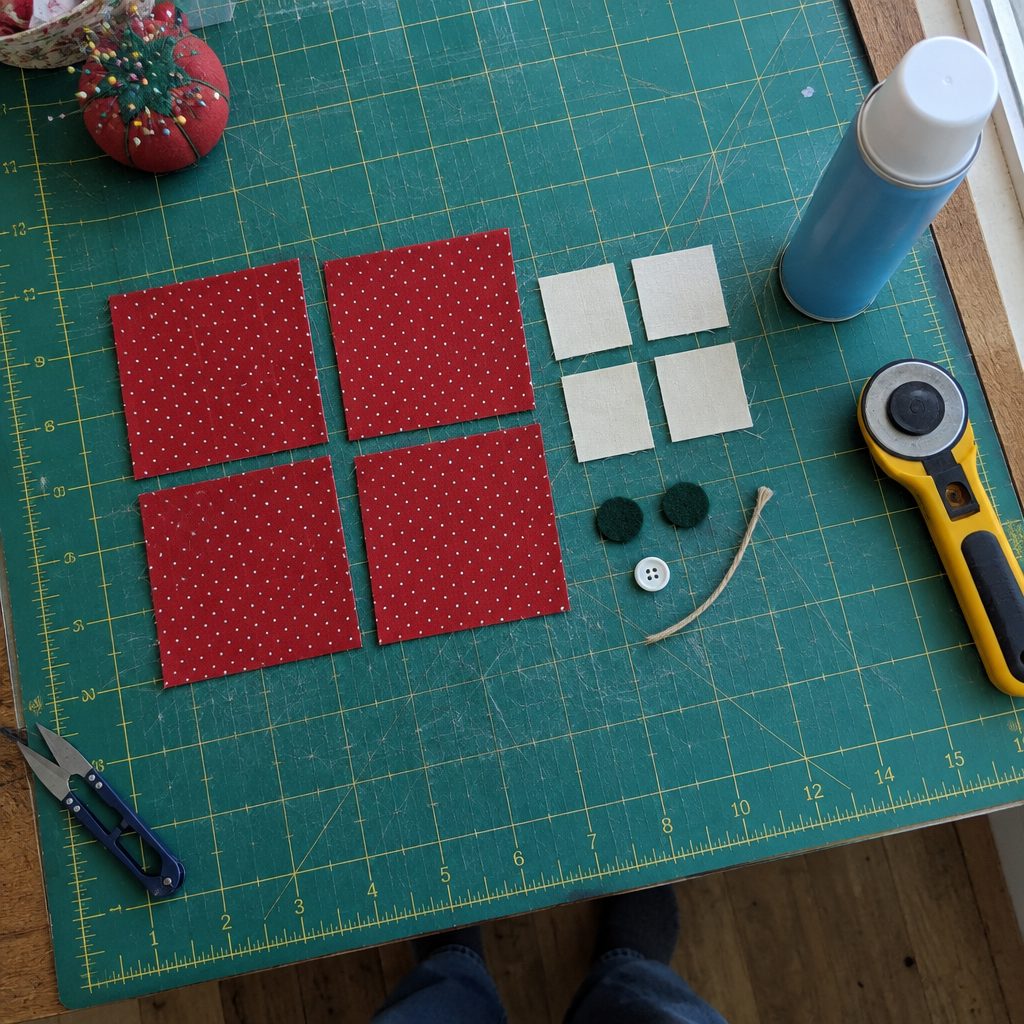 Cut cotton squares, felt circles, a button, twine, and spray starch laid out for a folded fabric star