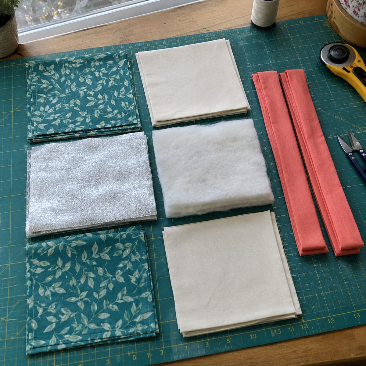 Cut squares of fabric, Insul-Bright, cotton batting and binding strips for quilted pot holders
