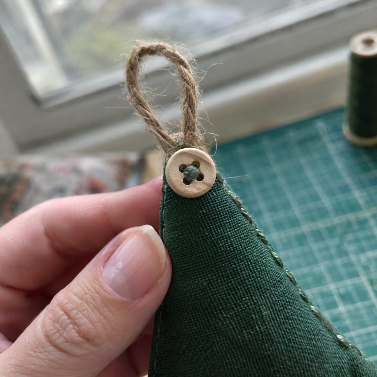 Close-up of the twine loop and wooden button at the tip of a fabric tree ornament